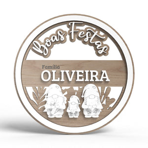 Decoração circular em madeira com a inscrição "Boas Festas" na parte superior e "Família OLIVEIRA" na parte central. Abaixo da inscrição da família, há três figuras de gnomos gravadas, cada uma com detalhes distintos, como barbas, chapéus e flores. A peça combina elementos em madeira natural e partes em MDF laminado de branco. Decoração circular em madeira com a inscrição "Boas Festas" na parte superior e "Família OLIVEIRA" na parte central. Abaixo da inscrição da família, há três figuras de gnomos gravadas, cada uma com detalhes distintos, como barbas, chapéus e flores. A peça combina elementos em madeira natural e partes em MDF laminado de branco.