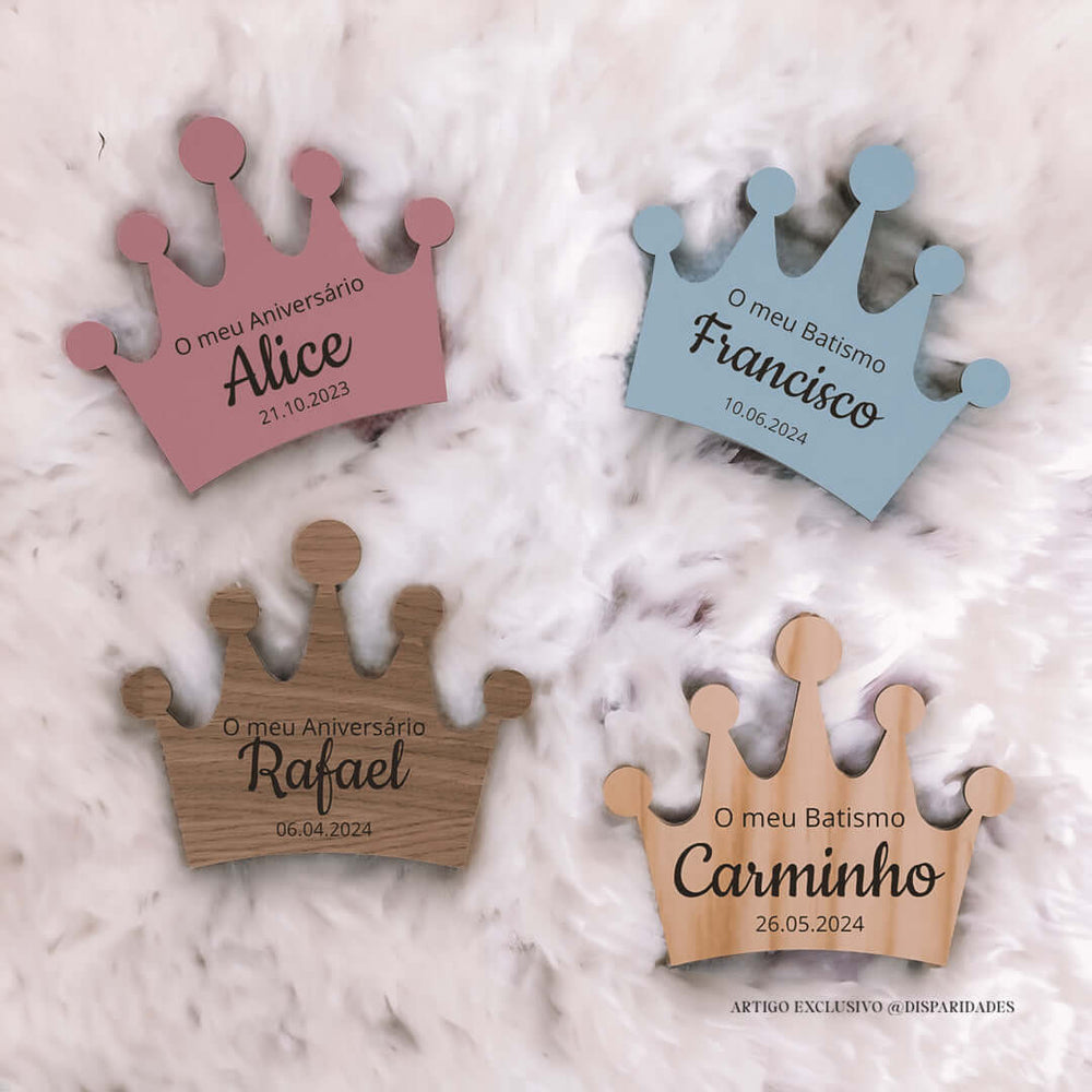 Quatro Lembranças em forma de coroas de madeira personalizadas com nomes e datas em um fundo de pelúcia branca.