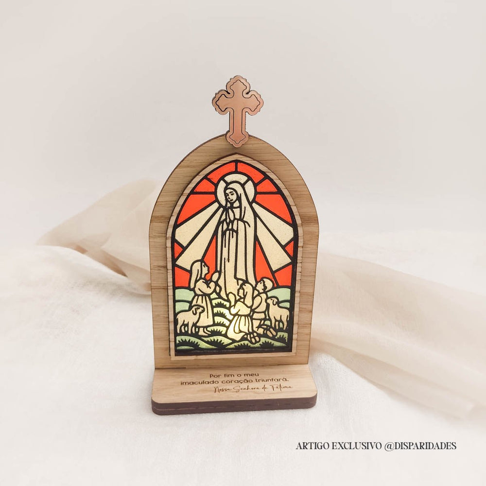 Oratório rústico em madeira com vitral colorido de Nossa Senhora de Fátima e a inscrição “Por fim o meu imaculado coração triunfará”.