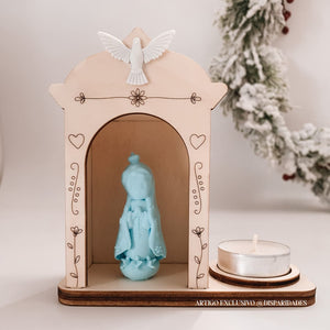 Pequeno oratório de madeira rústico com uma imagem azul de Nossa Senhora de Fátima e uma vela. No topo, uma pomba branca em destaque, com detalhes de corações e flores desenhados. Pequeno oratório de madeira rústico com uma imagem azul de Nossa Senhora de Fátima e uma vela. No topo, uma pomba branca em destaque, com detalhes de corações e flores desenhados.
