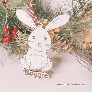 Pendente coelho com design minimalista em madeira, detalhes faciais simples e coração no peito. Pendura-se com fio vermelho e branco. Nome “Boggie” na base. Pendente coelho com design minimalista em madeira, detalhes faciais simples e coração no peito. Pendura-se com fio vermelho e branco. Nome “Boggie” na base.