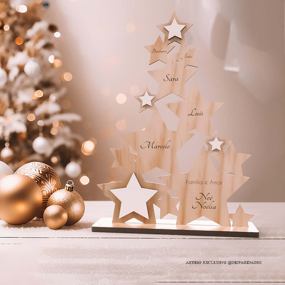 Árvore de Natal em pinho feita com formas de estrelas personalizado com os nomes da família e uma pequena frase "Família é Amor", está em cima de uma mesa ao lado de bolas de Natal douradas