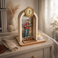 Oratório em madeira com imagem de Carlo Acutis, terço e vela LED sobre mesa decorativa.