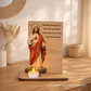 Placa de madeira com imagem do Sagrado Coração de Jesus e vela acesa, com oração religiosa gravada em português.
