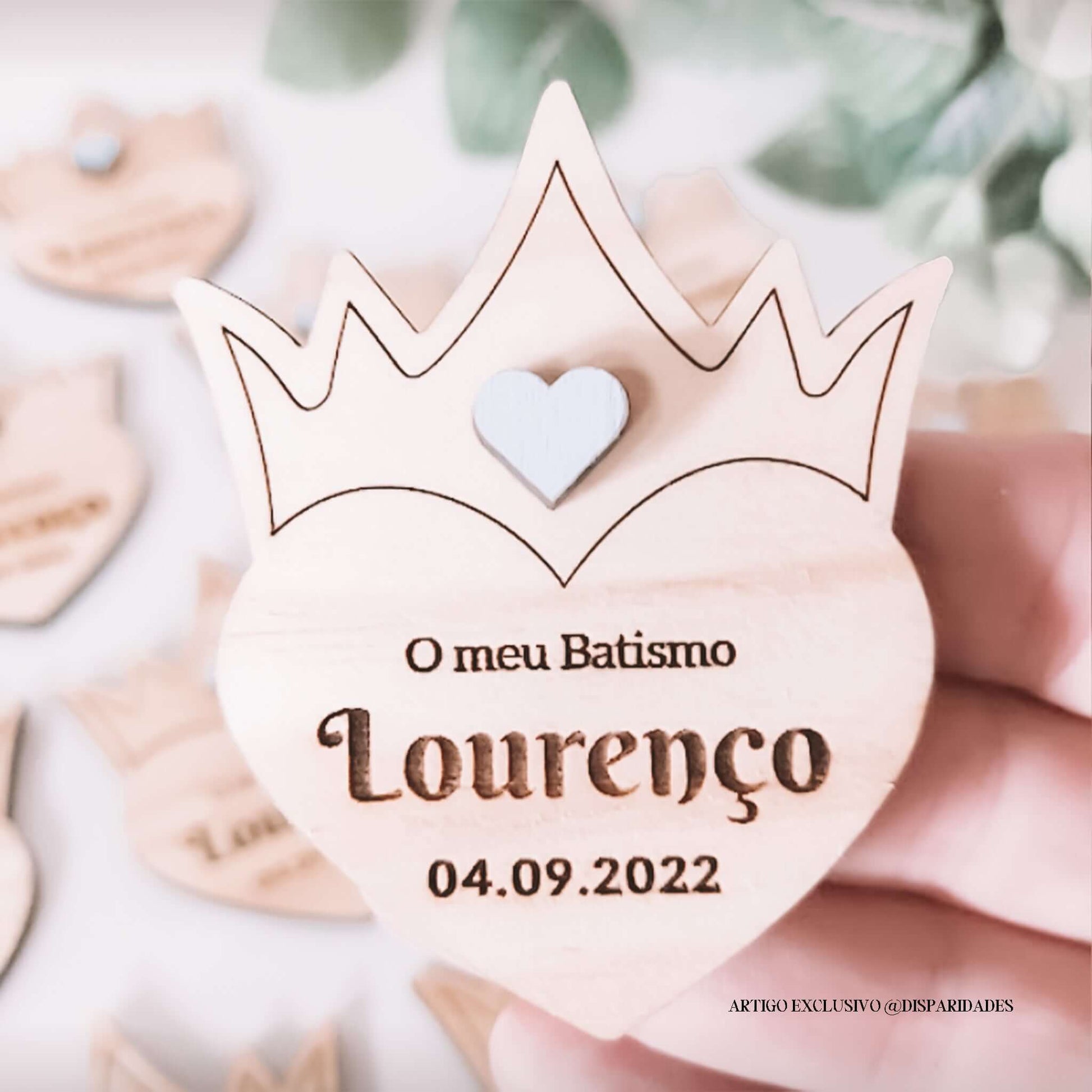uma mão a segurar uma lembrança de batismo crown em pinho com coração azul, nome apresentado na lembrança é Lourenço e a data 04.09.2022