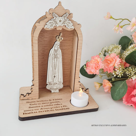 Oratório rústico de madeira com imagem de Nossa Senhora de Fátima e vela LED, junto a flores artificiais.