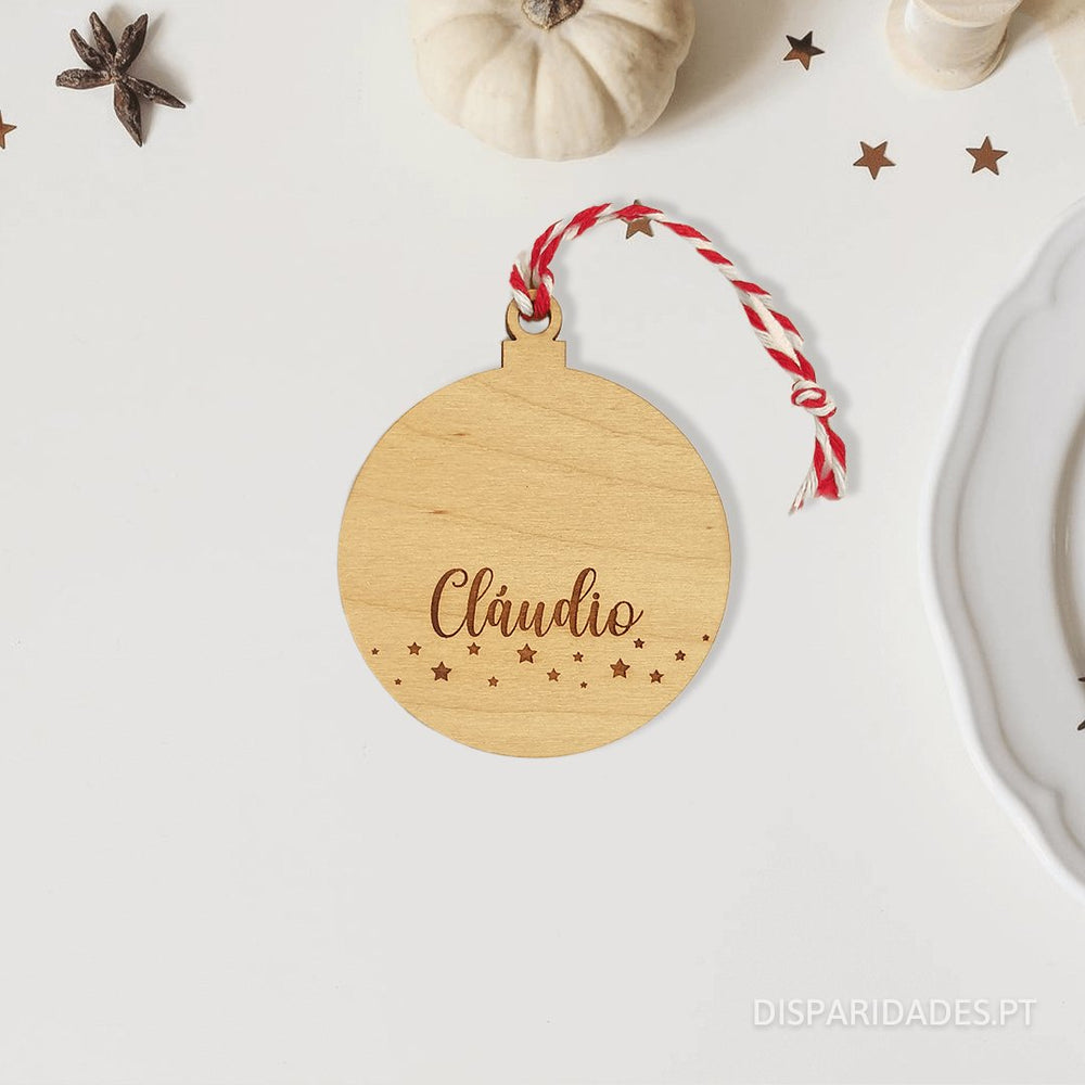 Bola de Natal em bétula com um fio para pendurar branco e vermelho em cima de uma mesa com pequenas estrela 