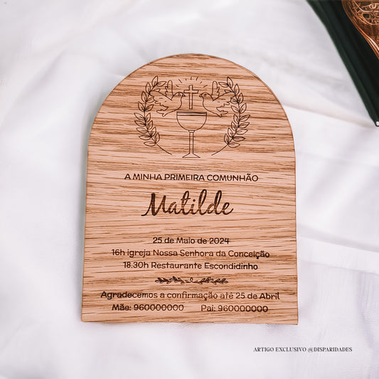 Convite de comunhão em madeira clara com texto e decoração gravados, sobre tecido branco.