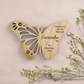 uma lembrança borboleta em pinho com ramos de flores ao lado