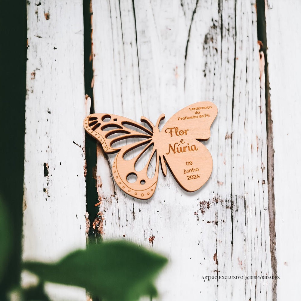 Lembrança em forma de borboleta gravado Flor e Núria com um fundo de madeira rústica