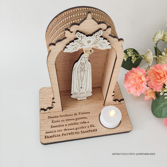 Oratório rústico de madeira com imagem de Nossa Senhora de Fátima e vela LED, junto a flores artificiais.