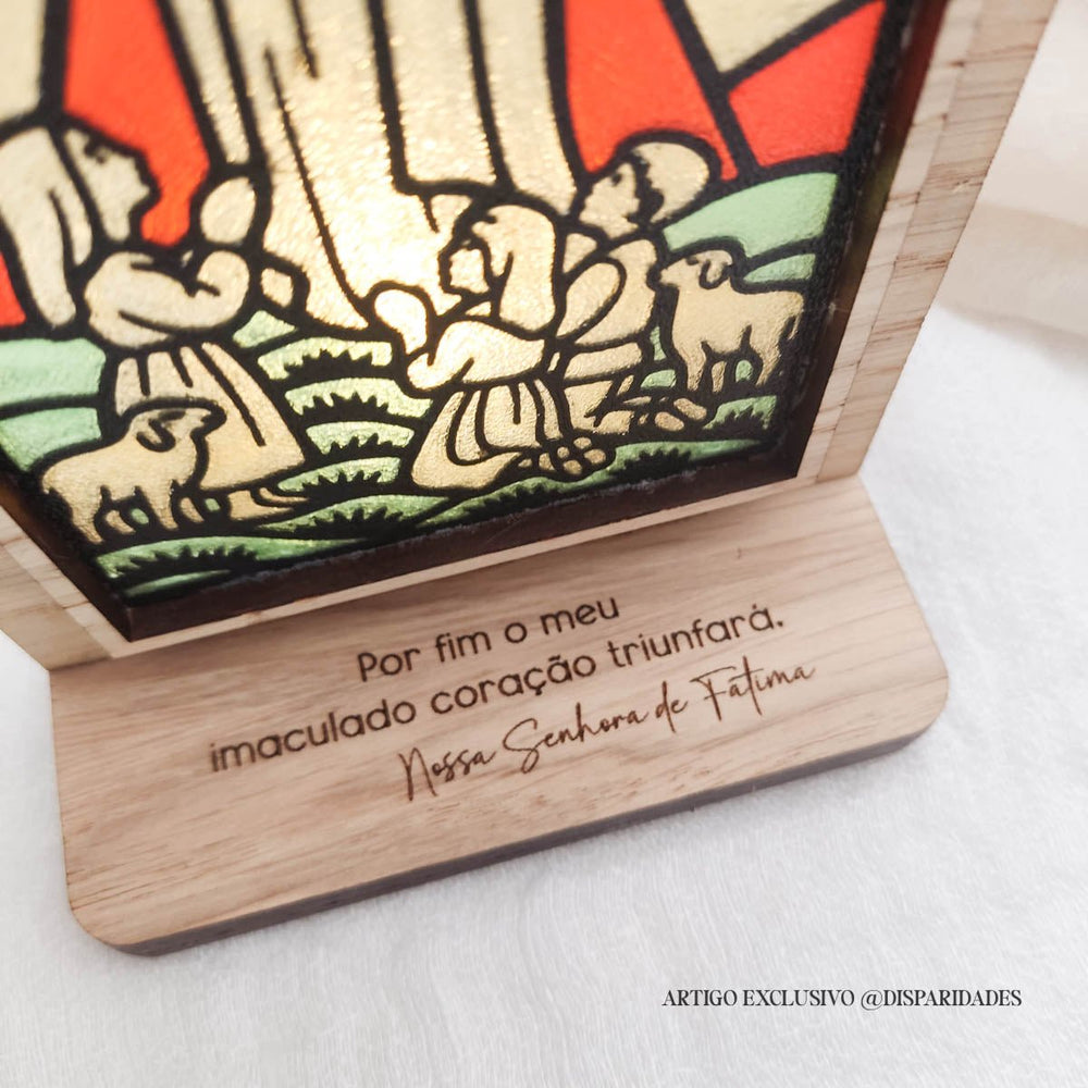 Oratório rústico em madeira com vitral colorido de Nossa Senhora de Fátima e a inscrição “Por fim o meu imaculado coração triunfará”.