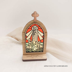 Oratório rústico em madeira com vitral colorido de Nossa Senhora de Fátima e a inscrição “Por fim o meu imaculado coração triunfará”.