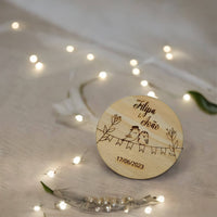 Lembrança de casamento 'Passarinhos Apaixonados' com Filipa & João gravado, sobre toalha bege com luzes LED.