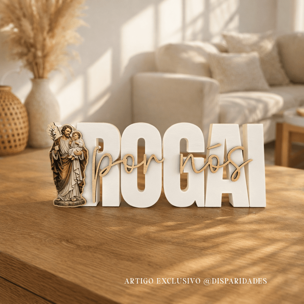 Placa rústica “Rogai por nós” em branco com letras em madeira e imagem religiosa de São José e o Menino Jesus, sobre mesa de madeira em sala acolhedora com sofá ao fundo.