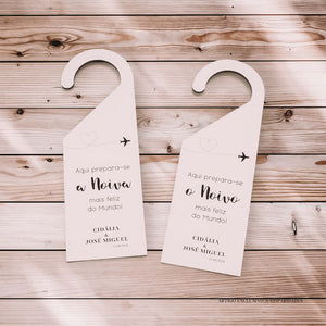 Placas decorativas em formato de cabide, com fundo de madeira rústica. À esquerda, "Aqui prepara-se a Noiva mais feliz do Mundo!" e à direita, "Aqui prepara-se o Noivo mais feliz do Mundo!", ambos para o casamento de Cidália e José Miguel, datado de 21.09.2024.